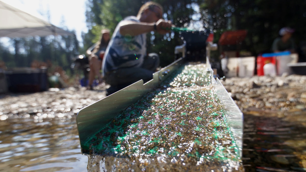A Dream Mat sluice mat running in a Montana creek with gold and black sand caught in the green cells